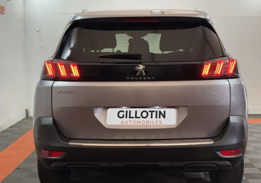 Vue arrière d'un Peugeot 5008 gris clair avec feux LED allumés dans un garage.