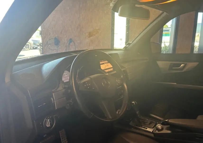 Vue intérieure côté conducteur du Mercedes GLK noir de 2012, mettant en valeur le volant cuir et la console centrale.