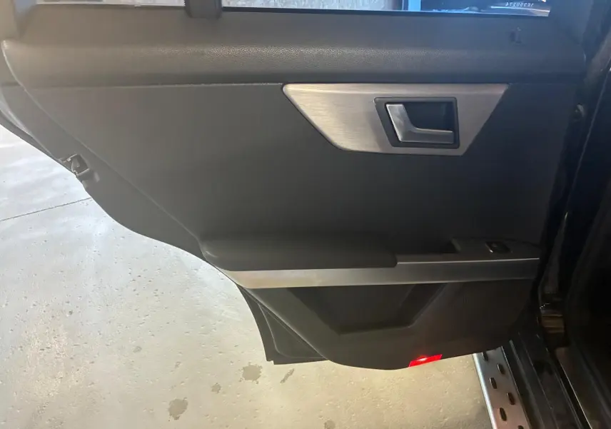 Vue intérieure de la porte arrière droite noire du Mercedes GLK 220 CDI avec insert aluminium et éclairage rouge.