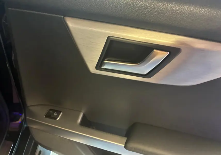 Gros plan sur la poignée intérieure côté gauche d’une Mercedes GLK noire avec bouton de commande de vitre.
