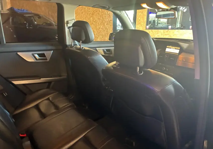 Vue intérieure arrière côté gauche du Mercedes GLK noir de 2012 avec sièges en cuir noir et tableau de bord visible.