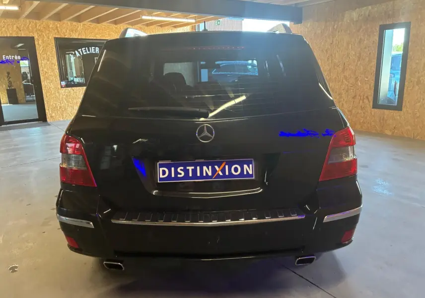 Vue arrière d'un Mercedes GLK noir 2012, avec feux rouges et double sortie d'échappement visible en intérieur d'atelier.