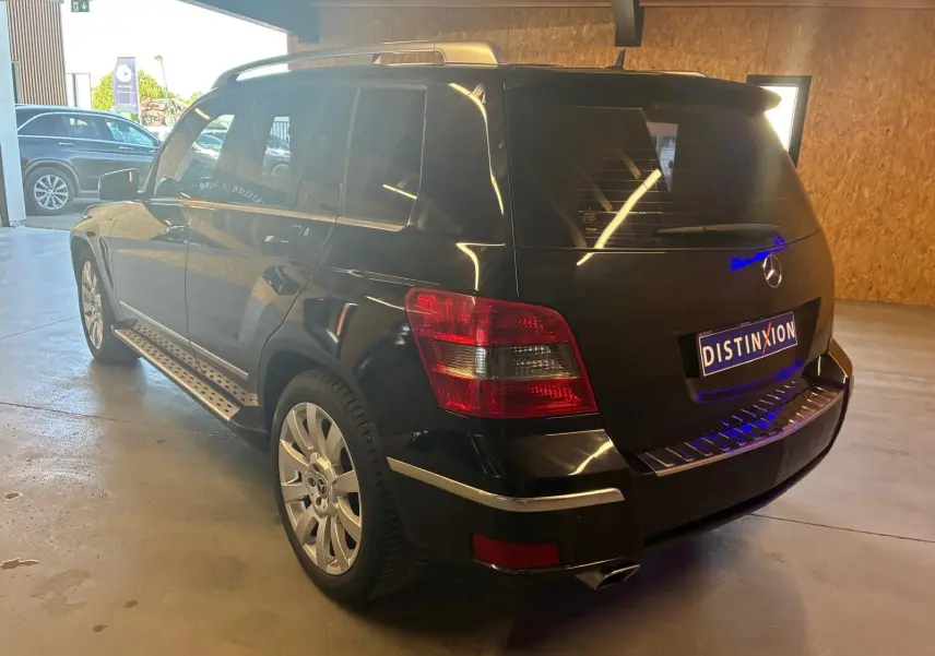 Mercedes GLK noir vu en 3/4 arrière droit, avec feux arrière rouges et jantes argentées dans un garage.