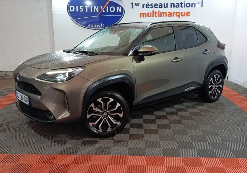 Toyota Yaris Cross gris foncé vue 3/4 avant droit, avec jantes alliage et phares LED allumés.