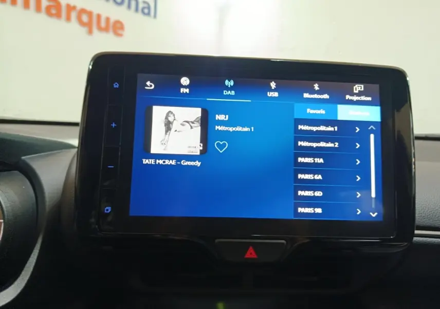 Écran tactile central affichant la radio DAB dans l'habitacle d'une Toyota Yaris Cross gris foncé, vue de face.