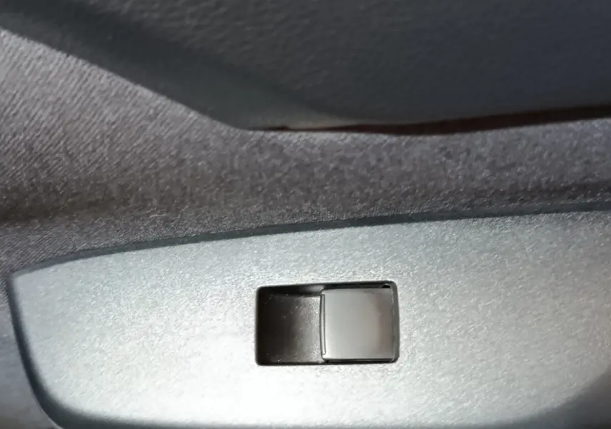 Gros plan sur l'interrupteur de lève-vitre côté porte intérieure d'une Toyota Yaris Cross gris foncé 2022.