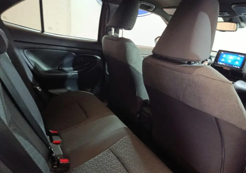 Vue intérieure arrière côté gauche de la Toyota Yaris Cross 2022, sièges tissu gris foncé avec écran tactile avant visible.