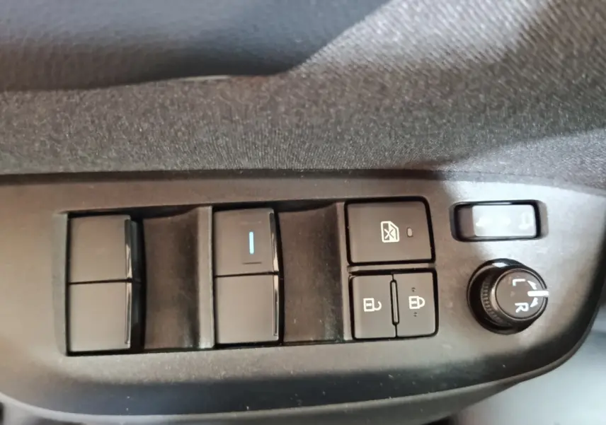 Gros plan sur les commandes de réglage des vitres et des rétroviseurs côté conducteur du Toyota Yaris Cross gris foncé 2022.