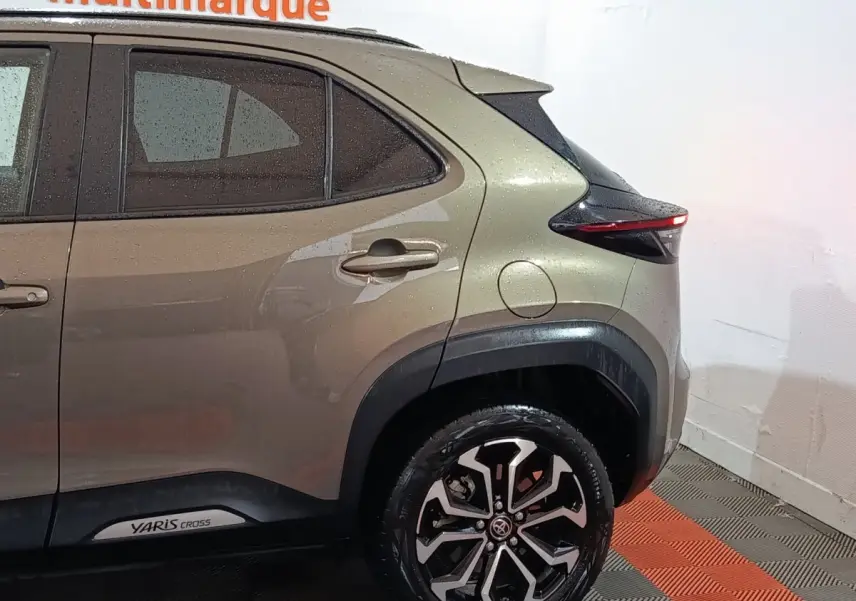 Vue côté droit arrière d’une Toyota Yaris Cross gris foncé avec jantes alliage et logo visible sur la porte arrière.