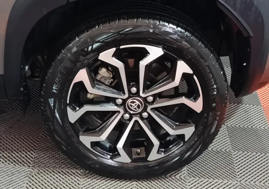 Gros plan sur la roue avant droite avec jante alliage noire et argentée du Toyota Yaris Cross gris foncé 2022.