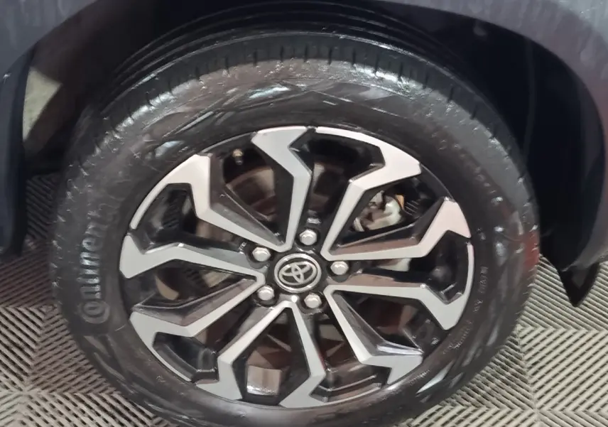 Gros plan sur la roue avant droite du Toyota Yaris Cross gris foncé, avec jante alliage au design géométrique noir et argent.