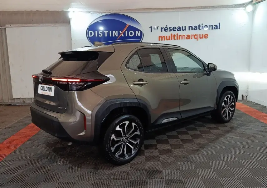 Vue 3/4 arrière droite d'une Toyota Yaris Cross gris foncé avec feux arrière LED et jantes alliage distinctives.