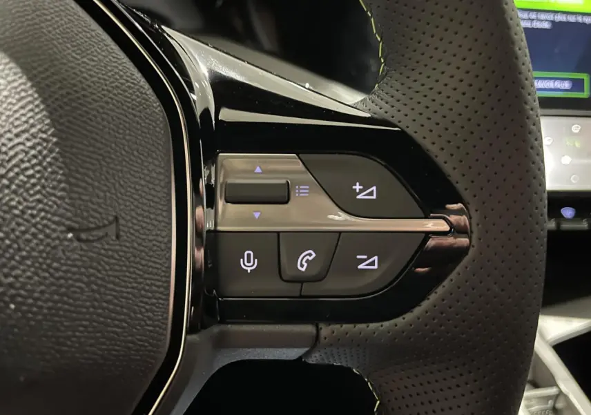 Gros plan sur les commandes du volant cuir perforé de la Peugeot 308 GT gris Selenium, avec éclairage des touches.