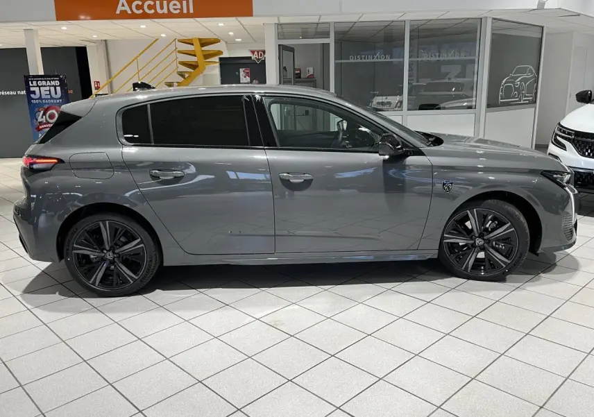 Peugeot 308 Gris Selenium vue de profil côté gauche en intérieur, avec jantes alliage noires et vitres surteintées.