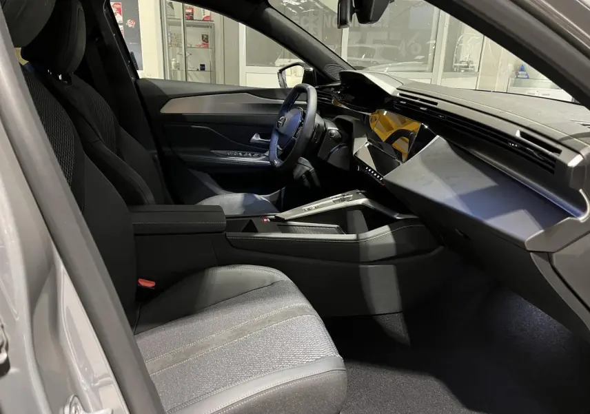 Intérieur avant droit de la Peugeot 308 2024 gris selenium, avec tableau de bord moderne et sellerie tri matières noire.