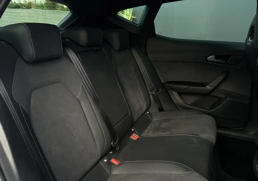 Vue latérale intérieure des sièges arrière en suédine noir Asphalte du CUPRA Formentor 2025 avec ceinture de sécurité visible.