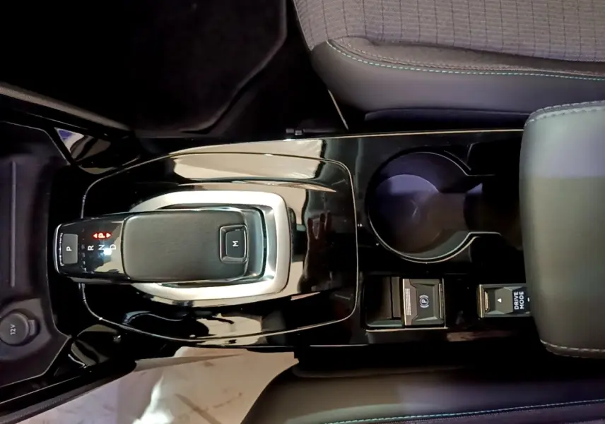 Vue rapprochée de la console centrale noire brillante du Peugeot 2008 blanc, avec levier de vitesse automatique et porte-gobelet.