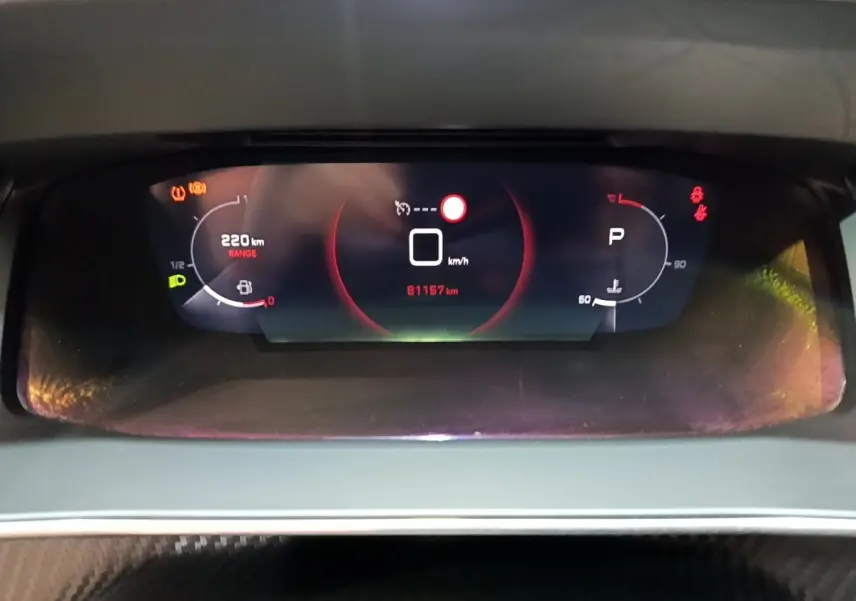 Vue rapprochée du tableau de bord numérique du Peugeot 2008 blanc, affichant la vitesse à 0 km/h et 91 157 km au compteur.
