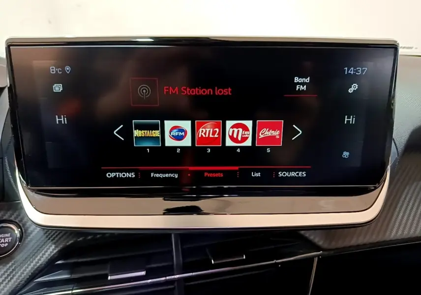 Écran tactile central du tableau de bord du Peugeot 2008 blanc, affichant les stations radio FM.