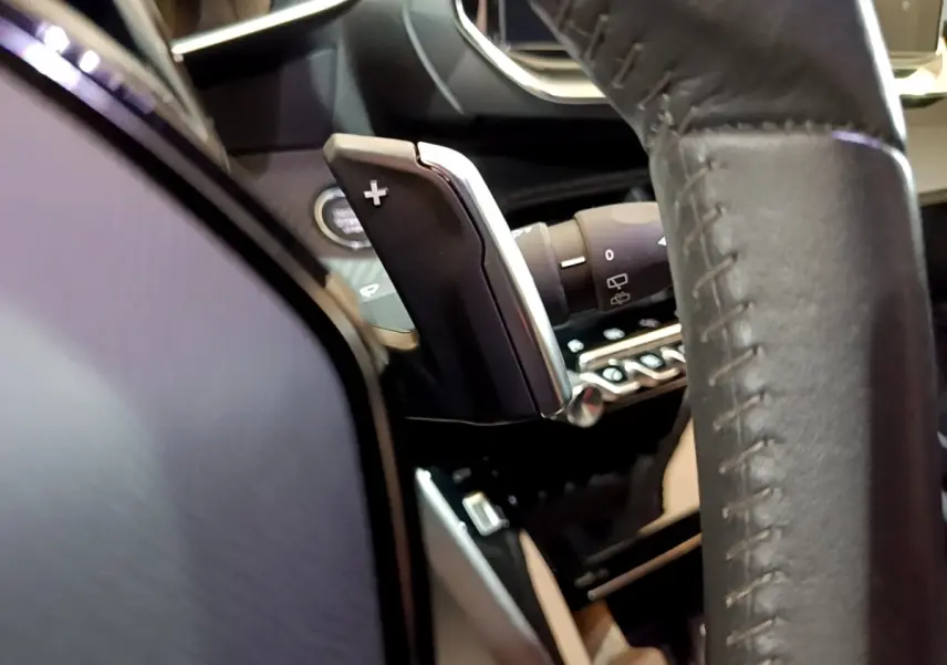 Gros plan sur la palette de changement de vitesse côté droit du volant cuir du Peugeot 2008 BlueHDi 130 blanc.