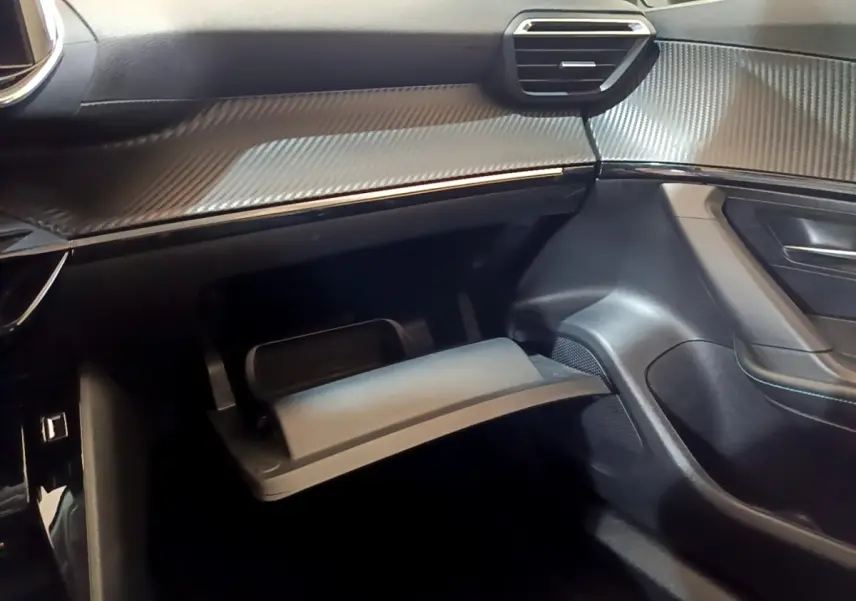 Vue intérieure côté passager du Peugeot 2008 blanc 2021, avec boîte à gants ouverte et tableau de bord noir texturé.