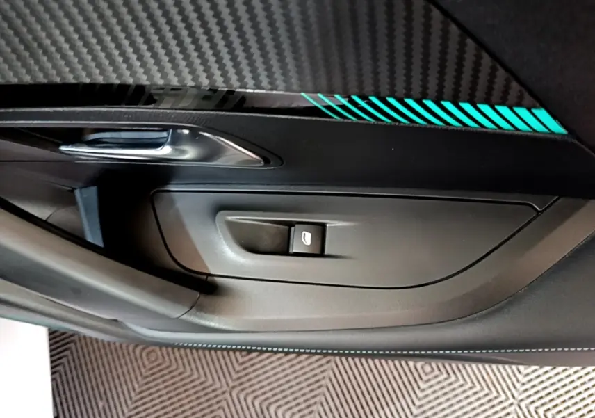 Détail de la porte intérieure côté gauche d’un Peugeot 2008 blanc, avec poignée argentée et bande décorative lumineuse bleue.