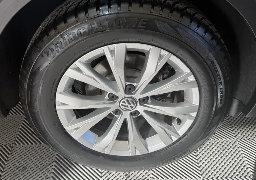 Gros plan sur la roue avant droite du Volkswagen Tiguan gris clair, mettant en valeur la jante alliage et le pneu Bridgestone.