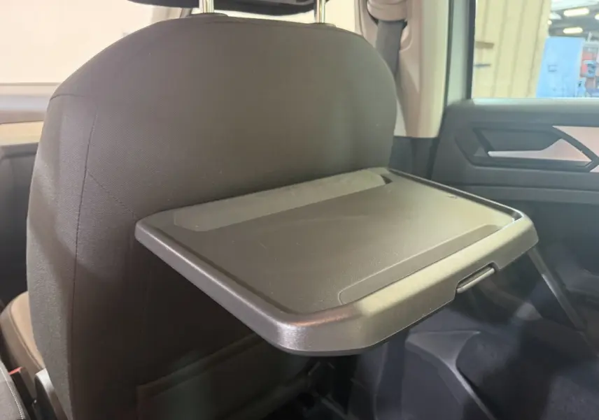 Vue intérieure côté arrière droit du Volkswagen Tiguan 2020, tablette rabattable fixée au dossier du siège avant noir.
