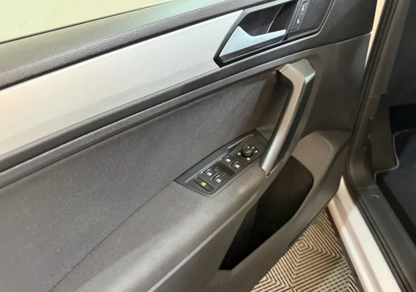 Vue rapprochée de la porte avant gauche du Volkswagen Tiguan 2020, avec commandes électriques et finition noire.