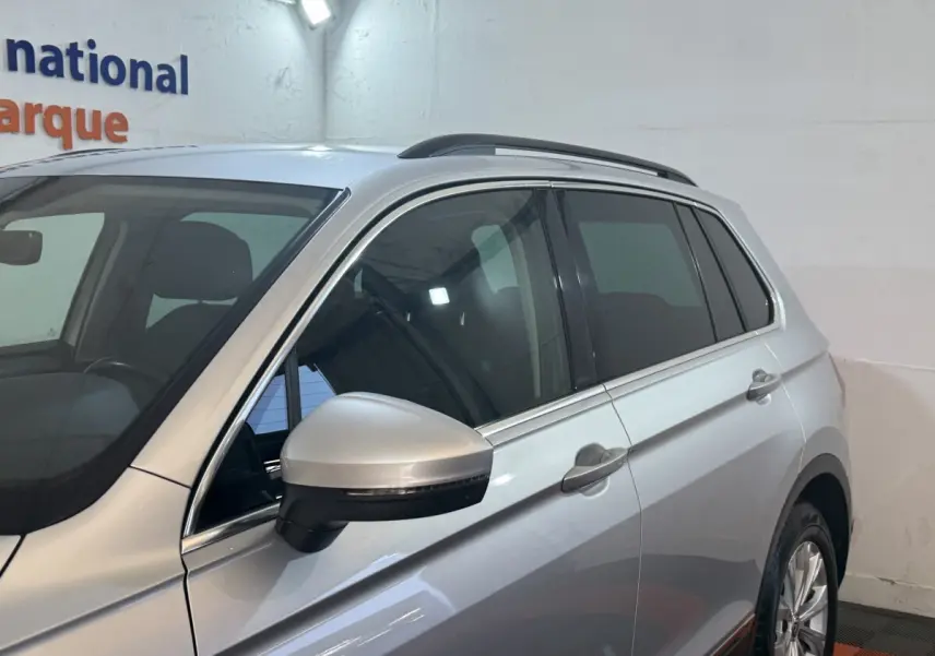 Vue côté gauche avant d'un Volkswagen Tiguan gris clair 2020 avec rétroviseur électrique et vitres teintées.