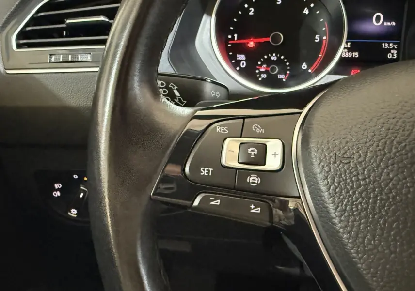 Gros plan sur le volant cuir multifonctions gris du Volkswagen Tiguan 2.0 TDI 150 DSG7 avec commandes de régulateur de vitesse.