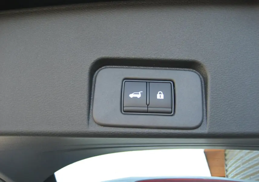 Boutons d'ouverture et de verrouillage du hayon sur la partie intérieure du coffre d'un Nissan X-TRAIL blanc nacré.
