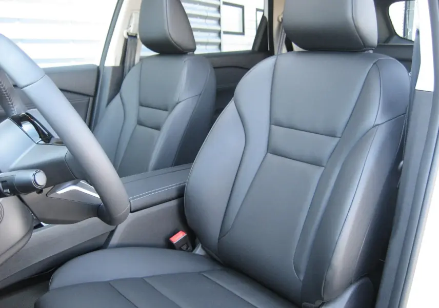Vue intérieure rapprochée des sièges avant en cuir noir du Nissan X-TRAIL blanc nacré, version 2026.
