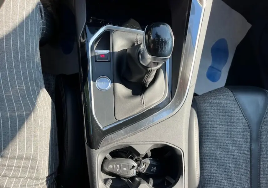 Vue plongeante sur la console centrale du Peugeot 3008 avec levier de vitesse manuel et porte-clés dans un porte-gobelet.