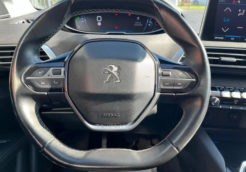 Vue rapprochée du volant noir du Peugeot 3008 2016 avec commandes intégrées et tableau de bord digital en arrière-plan.