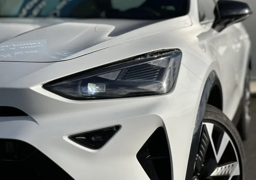 Gros plan sur l'avant droit blanc neige du CUPRA Formentor 2025, mettant en valeur son phare Tri-LED et jante alliage 19 pouces.