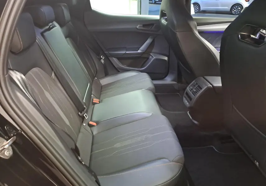 Vue intérieure côté gauche des sièges arrière noirs avec surpiqûres orange dans une CUPRA Leon 2023 Noir Minuit.