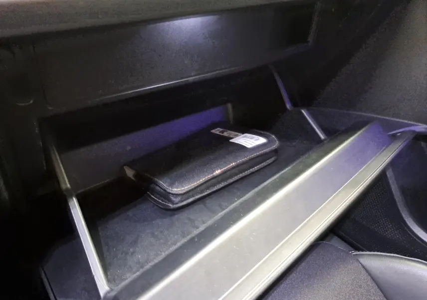 Gros plan sur la boîte à gants ouverte de la CUPRA Leon 2023 noir minuit avec un étui noir à l'intérieur.