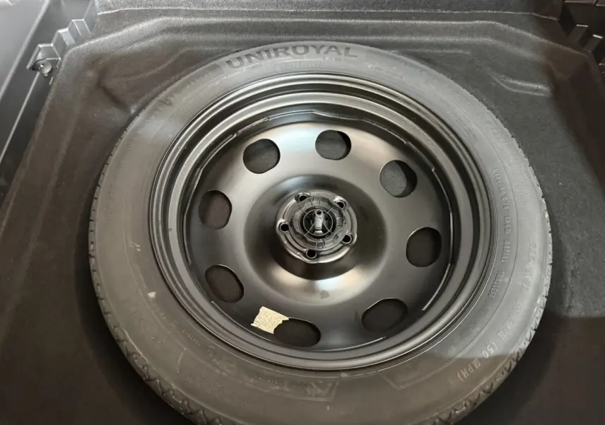 Roue de secours noire Uniroyal dans le coffre d'un Citroën C5 Aircross bleu, vue en plongée.