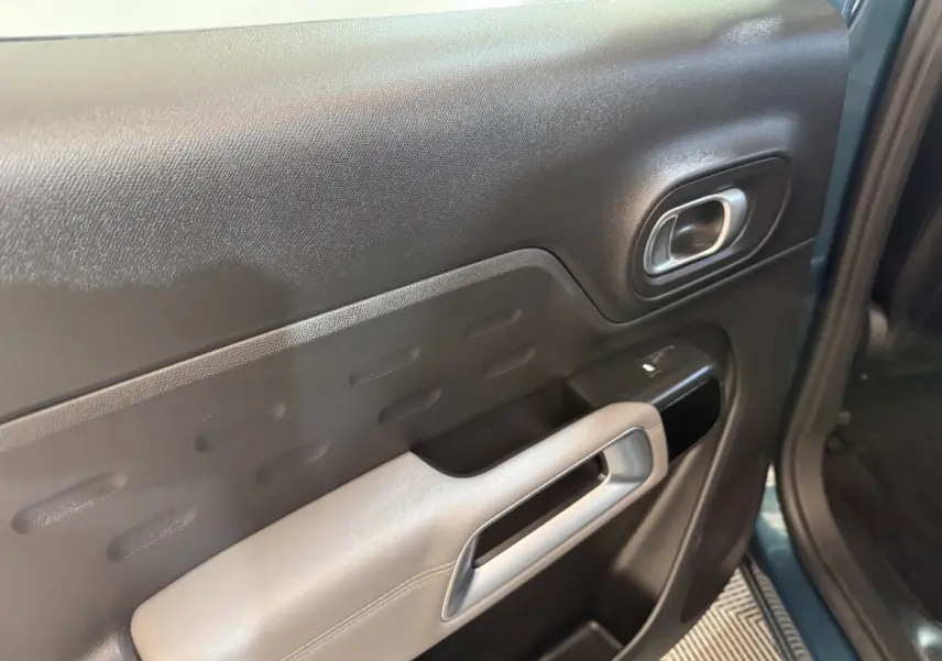 Vue rapprochée de la porte avant gauche bleu foncé du Citroën C5 Aircross avec poignée argentée et commande de vitre.