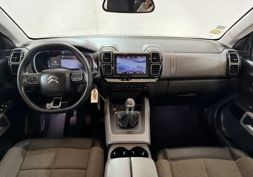 Vue intérieure frontale du tableau de bord et volant cuir noir du Citroën C5 Aircross avec écran tactile et levier de vitesses manuel.