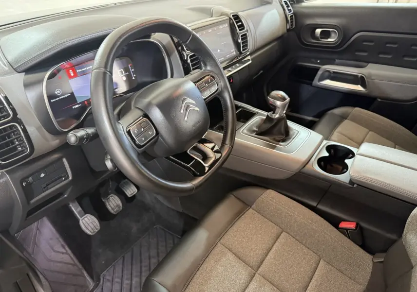 Vue intérieure côté conducteur du Citroën C5 Aircross avec volant cuir multifonctions et levier de vitesse manuel.