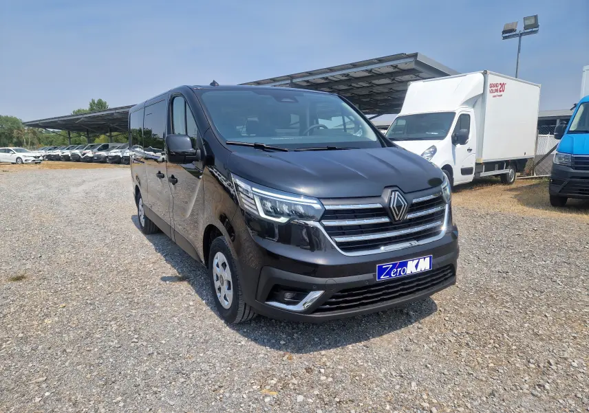 Renault Trafic Combi noir vu en 3/4 avant droit sur parking, avec calandre chromée et plaque Zero KM visible.