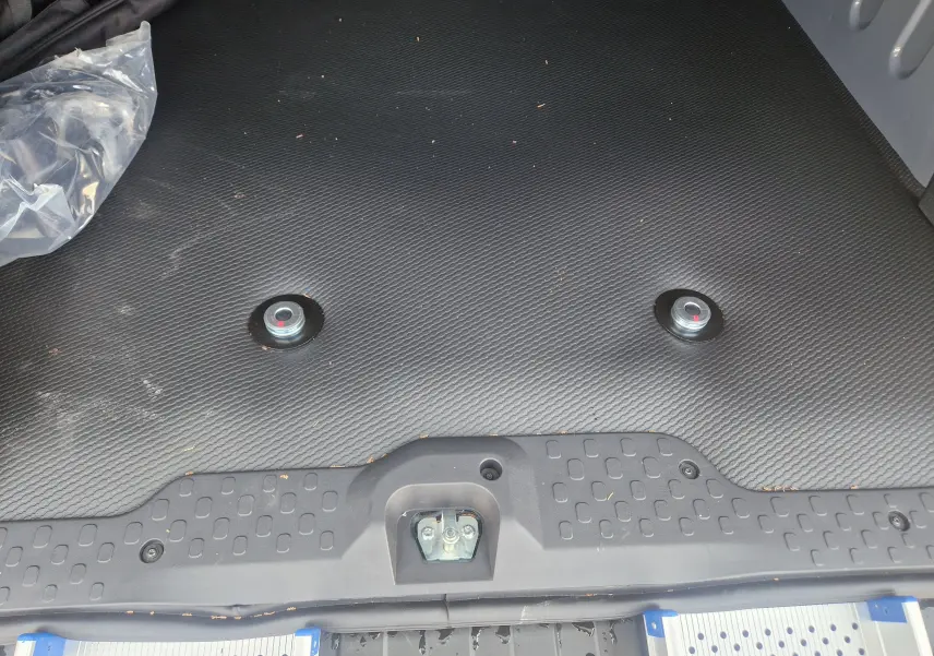 Vue rapprochée du plancher noir avec plots d’arrimage pour fauteuil roulant dans le coffre du Renault Trafic Combi 2026.