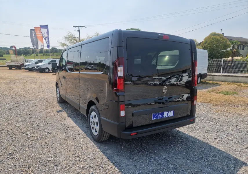 Vue 3/4 arrière droite du Renault Trafic Combi noir 2026, avec vitres teintées et hayon fermé sur parking extérieur.