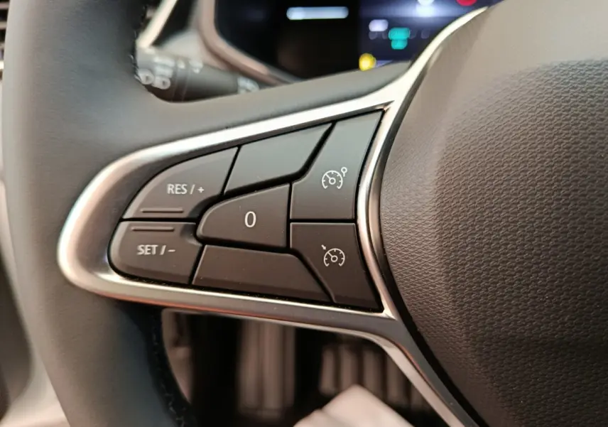 Gros plan sur les commandes du régulateur de vitesse au volant cuir synthétique d’une Renault Clio blanche 2024.