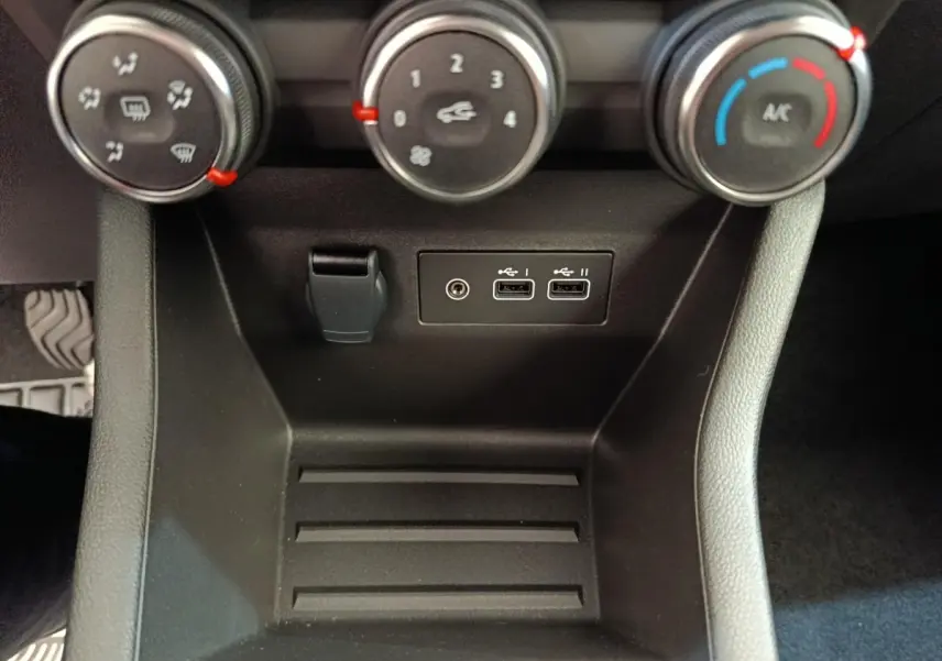Vue rapprochée de la console centrale noire de la Renault Clio 2024 avec commandes climatisation et ports USB.