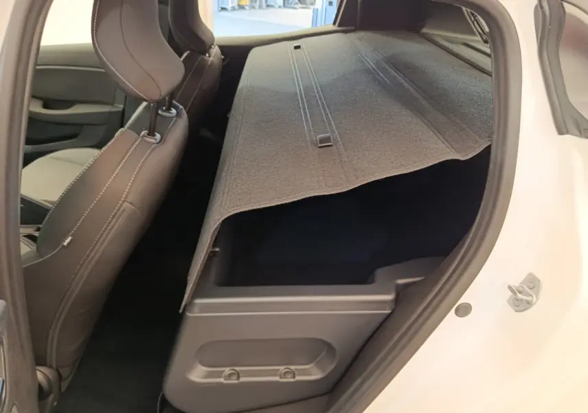Vue intérieure côté droit de la Renault Clio blanche 2024 montrant le coffre sous la banquette arrière rabattue.