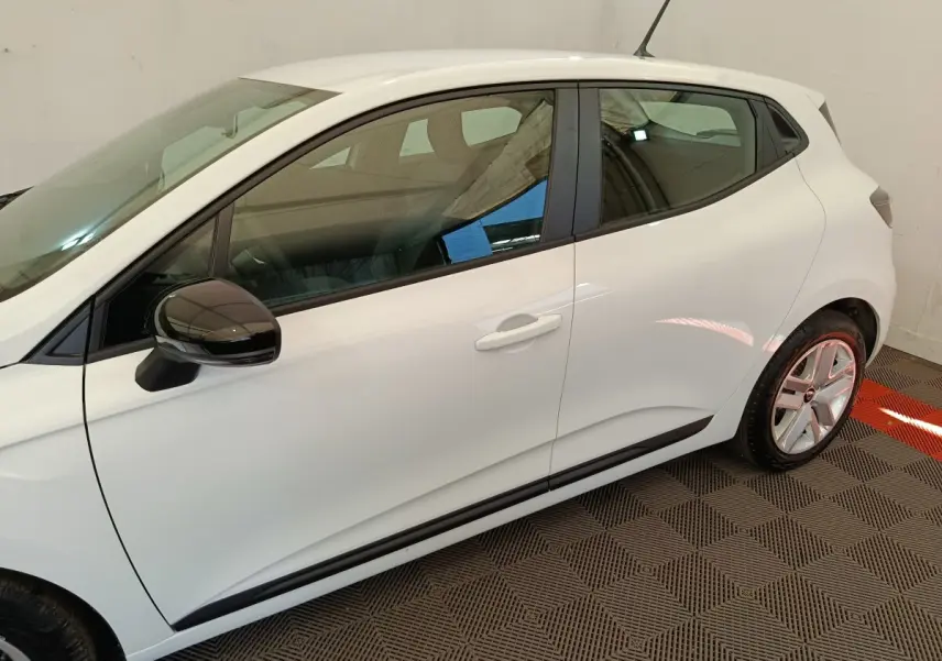 Vue latérale côté gauche d'une Renault Clio blanche 2024 avec rétroviseur noir et jantes alliage.
