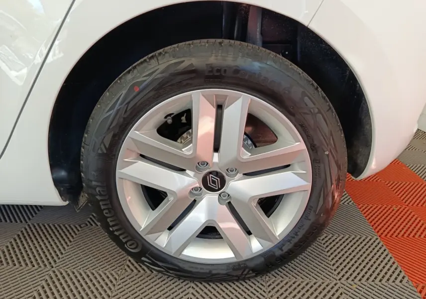 Gros plan sur la roue avant droite d'une Renault Clio blanche avec jante alliage à cinq branches.